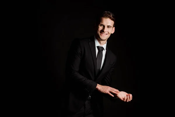Feliz hombre de negocios en traje sonriendo aislado en negro - foto de stock