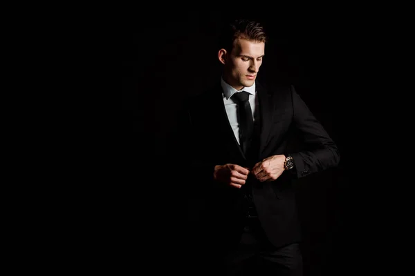 Selbstbewusster Mann, der formale Kleidung isoliert auf Schwarz anfasst — Stockfoto