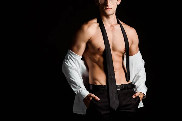 Обрізаний вид роздягненого чоловіка, що стоїть руками в кишенях ізольовано на чорному — стокове фото