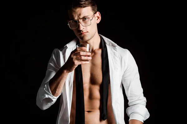 Sexy Mann in Brille und Anzug hält Glas mit Whiskey isoliert auf schwarz — Stockfoto