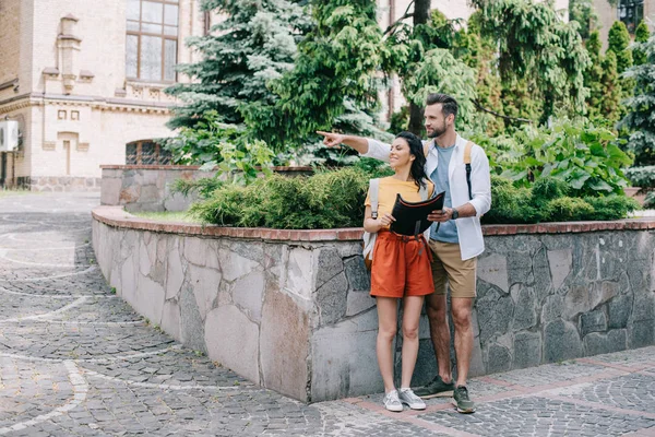 Щасливий чоловік вказує пальцем, тримаючи карту і стоячи з дівчиною — стокове фото