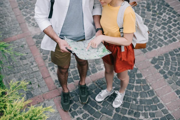 Ausgeschnittene Ansicht einer Frau, die mit dem Finger auf Landkarte in der Nähe eines Mannes zeigt — Stockfoto