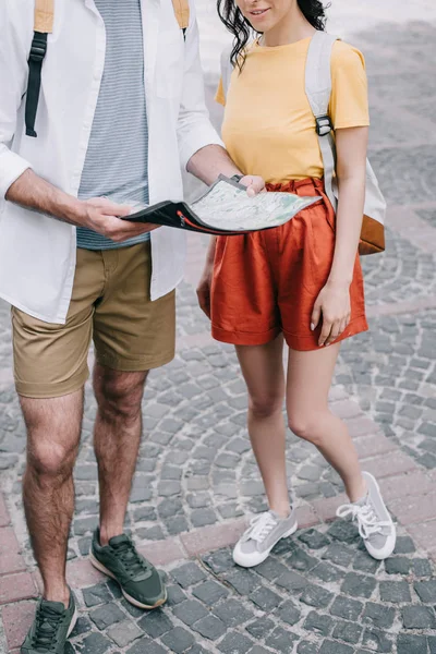 Vista recortada de la niña de pie con el hombre sosteniendo mapa - foto de stock