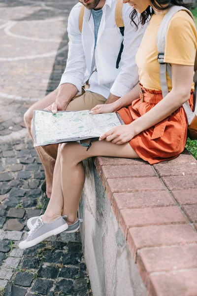 Cropped view of man and woman sitting with map — Stock Photo