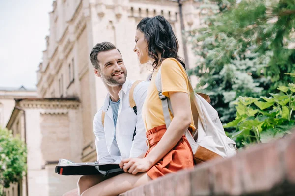 Enfoque selectivo de hombre barbudo feliz sosteniendo mapa y mirando a la mujer - foto de stock