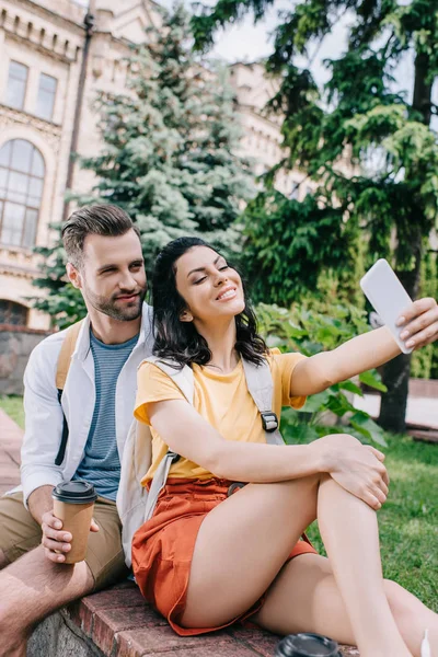 Happy woman talking selfie with handsome man near building — Stock Photo