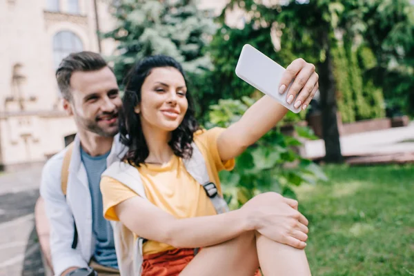 Foyer sélectif de femme heureuse parler selfie avec bel homme près de la construction — Photo de stock