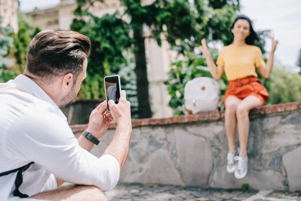 Enfoque selectivo del hombre que sostiene el teléfono inteligente con pantalla en blanco cerca de la mujer feliz - foto de stock