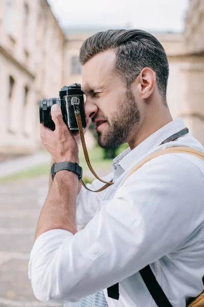 Vue latérale de l'homme barbu prenant des photos sur appareil photo numérique — Photo de stock