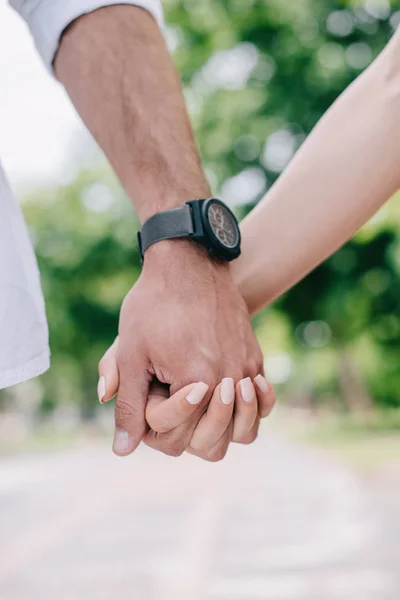 Vista recortada del hombre y la mujer tomados de la mano - foto de stock