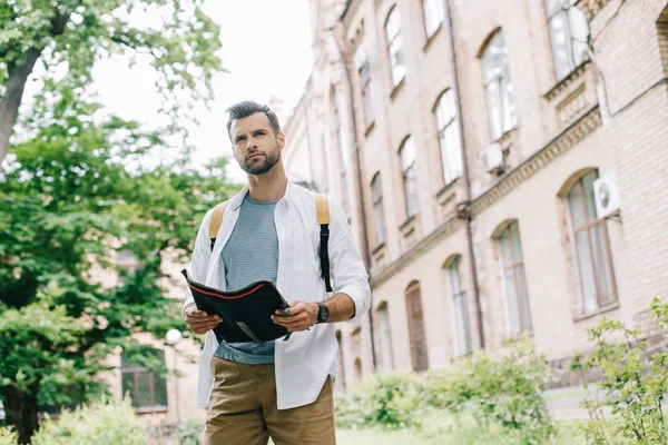 Handsome bearded traveler holding map near building — Stock Photo