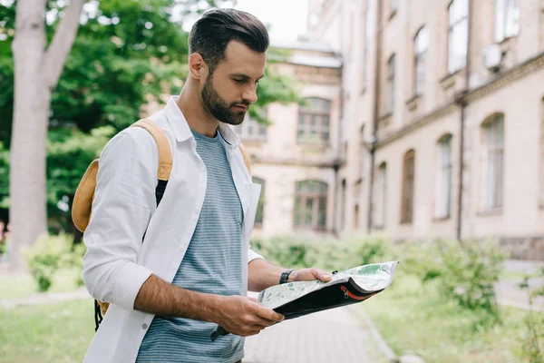 Handsome bearded tourist holding map near building — Stock Photo