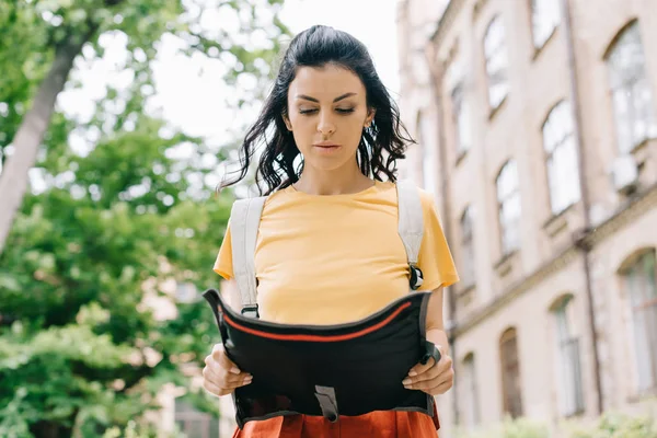 Low angle view of attractive young woman looking at map near building — Stock Photo