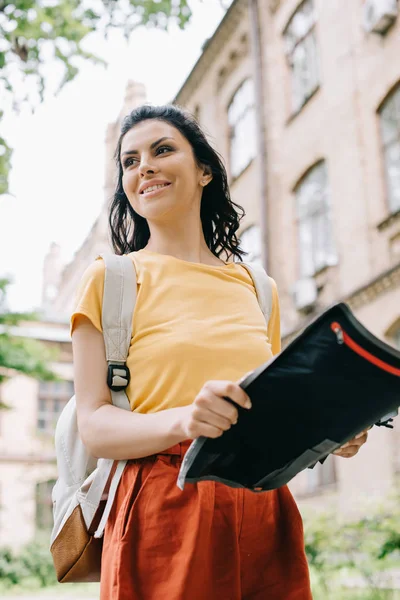 Tiefansicht einer fröhlichen Frau, die eine Karte in der Nähe eines Gebäudes hält — Stockfoto