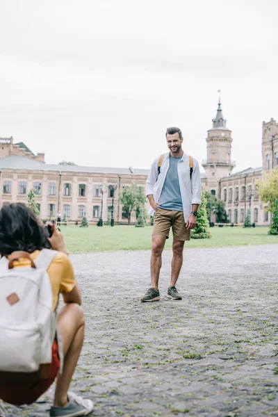 Селективный фокус счастливого мужчины, стоящего рядом с девушкой и фотографирующего — стоковое фото
