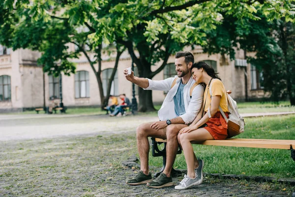 Hombre feliz tomando selfie con la mujer joven en el teléfono inteligente - foto de stock