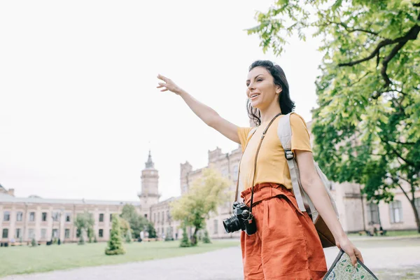 Счастливая девушка жестикулирует, держа карту возле здания — стоковое фото