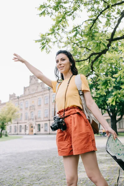 Счастливая женщина жестикулирует, держа карту возле здания — стоковое фото