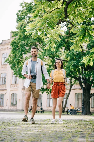 Happy man holding hands with girl while walking near building — Stock Photo