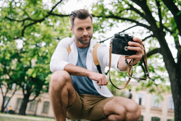 Low angle view of happy bearded man taking selfie on digital camera near building — Stock Photo