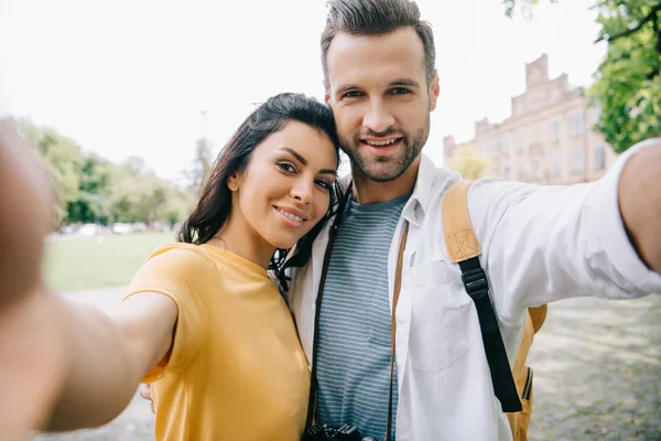 Selektiver Fokus glücklicher Männer und Frauen, die in der Nähe von Gebäuden in die Kamera schauen — Stockfoto