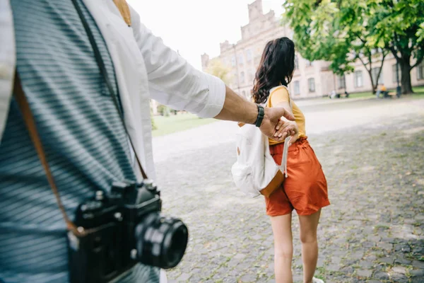 Cropped view of man holding hands with girl walking near university — Stock Photo