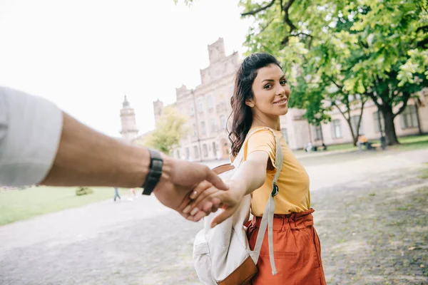 Cropped view of man holding hands with attractive girl walking near university — Stock Photo