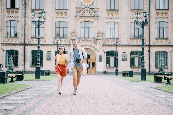 Coupon felice che si tiene per mano mentre si cammina vicino al campus universitario — Foto stock