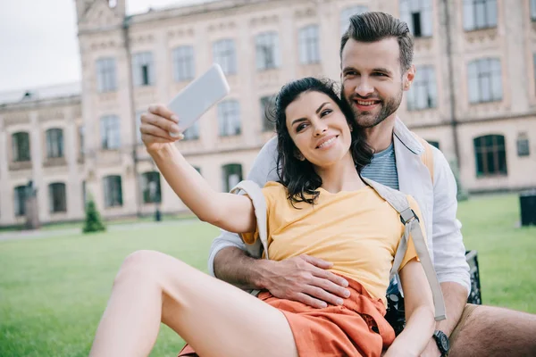 Foco seletivo de casal alegre tomando selfie perto do edifício — Fotografia de Stock