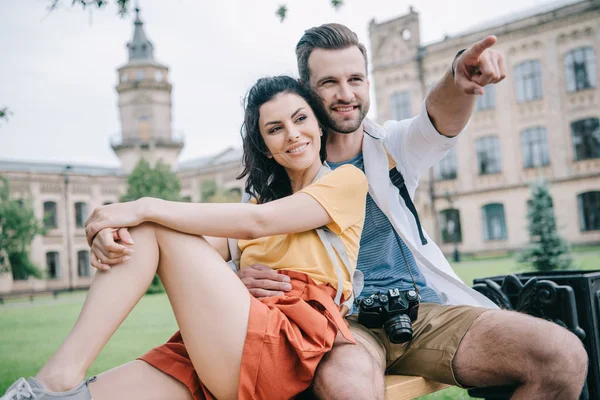 Hombre feliz señalando con el dedo mientras está sentado con hermosa chica - foto de stock