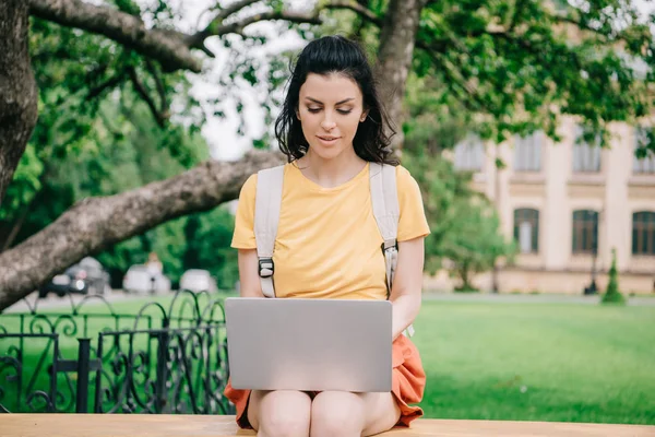 Attraktive Frau sitzt auf Bank und benutzt Laptop — Stockfoto