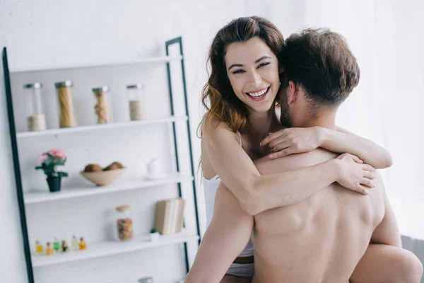 Back view of boyfriend holding smiling and attractive girlfriend in apartment — Stock Photo