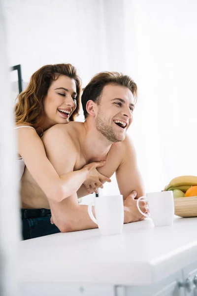 Attractive girlfriend and handsome boyfriend smiling and hugging in apartment — Stock Photo