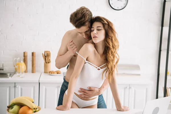 Attractive girlfriend with closed eyes and handsome boyfriend hugging in apartment — Stock Photo