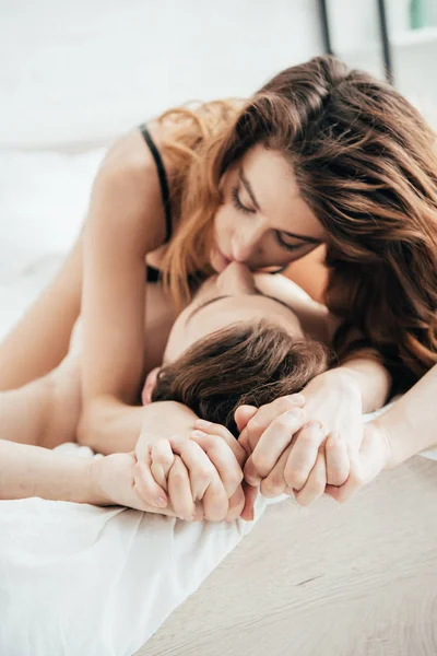 Jolie petite amie en sous-vêtements noirs câlins et baisers petit ami au lit — Photo de stock