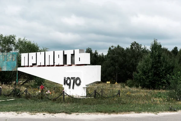 PRIPYAT, UCRÂNIA - AGOSTO 15, 2019: monumento com letras pripyat perto de árvores fora — Fotografia de Stock