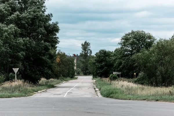 Arbres verts près de l'asphalte sur la route contre le ciel avec des nuages — Photo de stock
