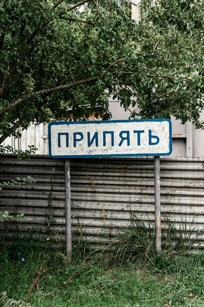 ПРИПЯТ, УКРАИНА - 15 АВГУСТА 2019 года: знак с припятскими надписями возле забора и деревьев — стоковое фото