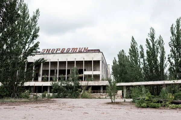 PRIPYAT, UCRÂNIA - AGOSTO 15, 2019: construção com letras energéticas perto de árvores verdes em chernobyl — Fotografia de Stock