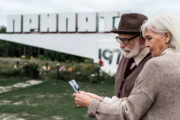 PRIPYAT, UKRAINE - AUGUST 15, 2019: retired couple holding black and white photo — Stock Photo