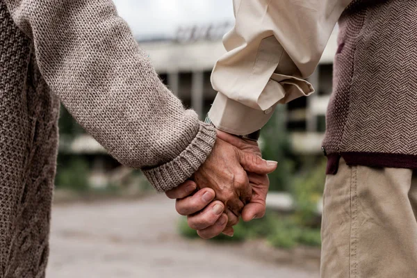 Vista recortada del hombre y la mujer jubilados tomados de la mano - foto de stock