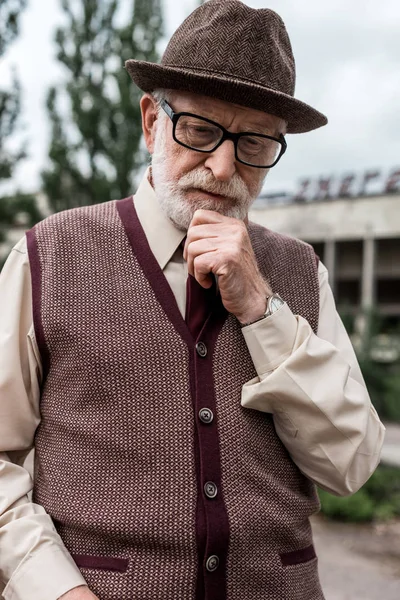 Pensive senior man standing near building in chernobyl — Stock Photo