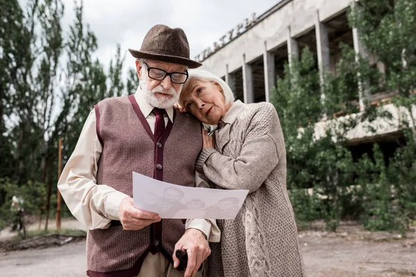 Pripjat, Ukraine - 15. August 2019: älteres Ehepaar betrachtet Foto in der Nähe eines Gebäudes in Tschernobyl — Stockfoto