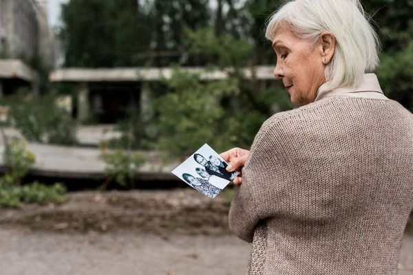 ПРИПЯТ, Украина - 15 августа 2019 года: пожилая женщина с седыми волосами смотрит на черно-белое фото — стоковое фото