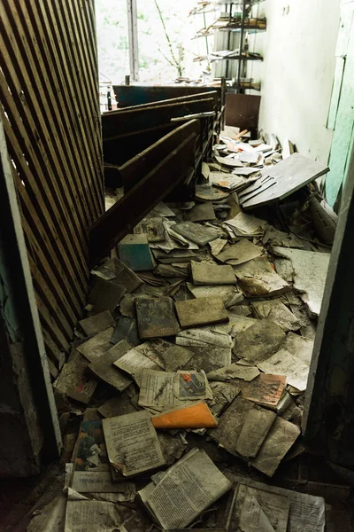 PRIPYAT, UCRANIA - 15 de agosto de 2019: aula sucia y abandonada con libros en el suelo de la escuela - foto de stock