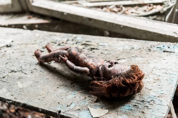 Foco selectivo de muñeca sucia y quemada en escritorio dañado de madera - foto de stock