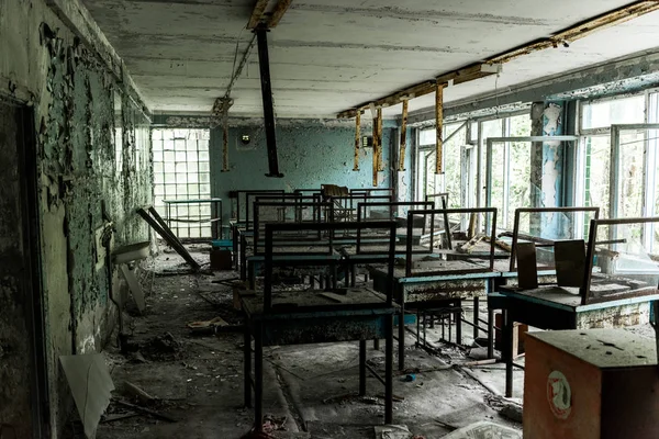 Abandoned and creepy classroom with dirty tables in school — Stock Photo