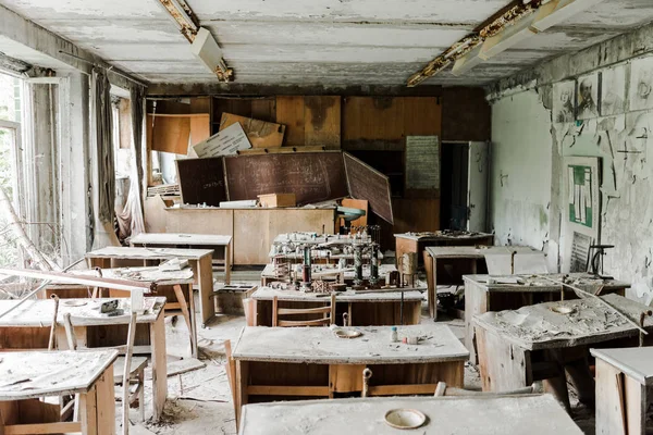 Verlassenes und gruseliges Klassenzimmer mit schmutzigen Tischen und Kreidetafel in der Schule — Stockfoto