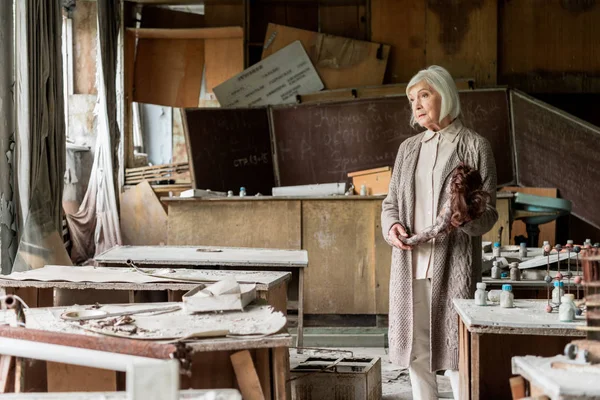 Foyer sélectif de la femme âgée avec des cheveux gris tenant poupée sale — Photo de stock