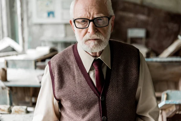 Бородатий пенсіонер в окулярах дивиться на камеру — стокове фото